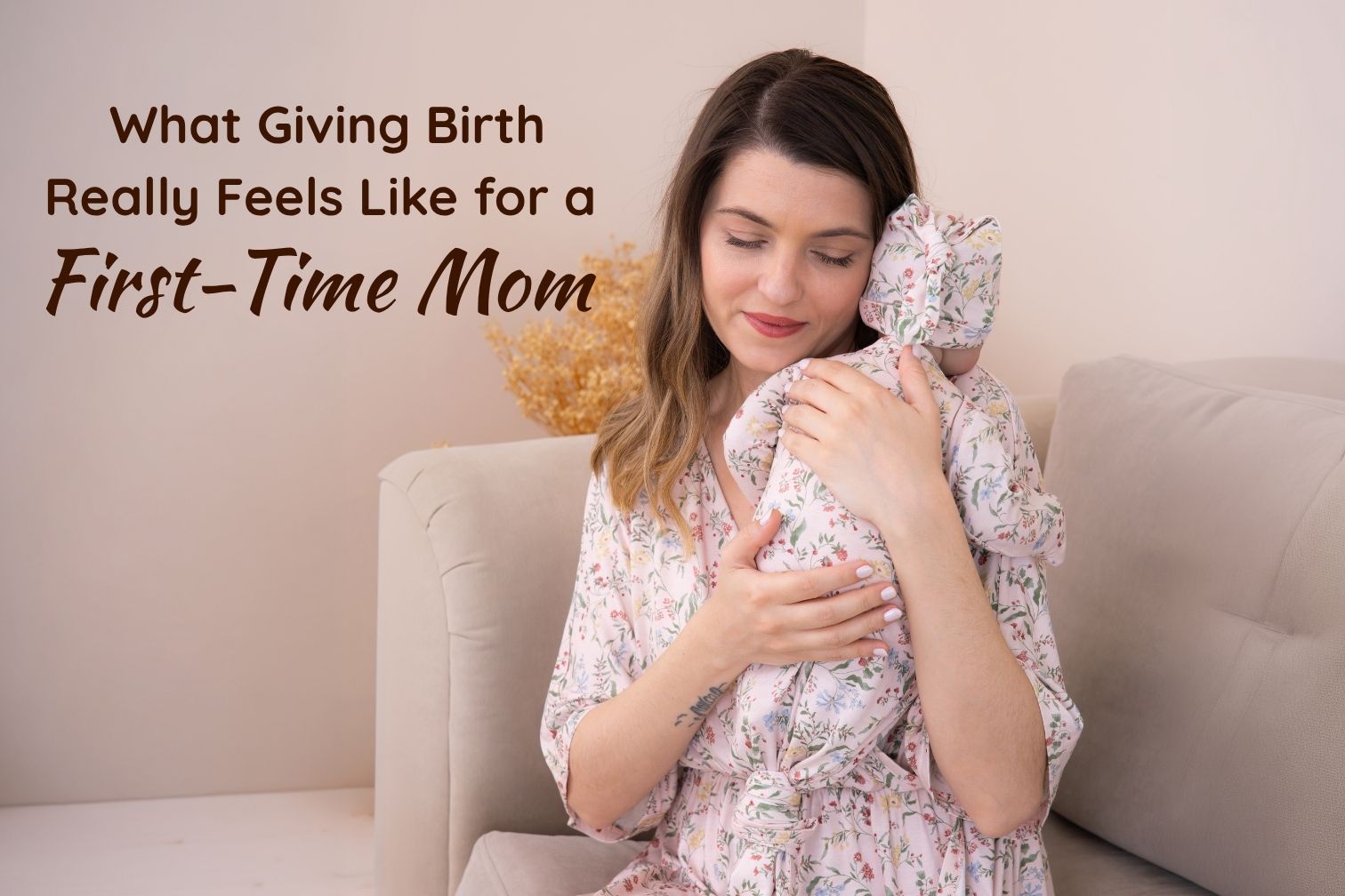 a new mother in a botanical maternity dress gently cradling her swaddled newborn while sitting on a couch
