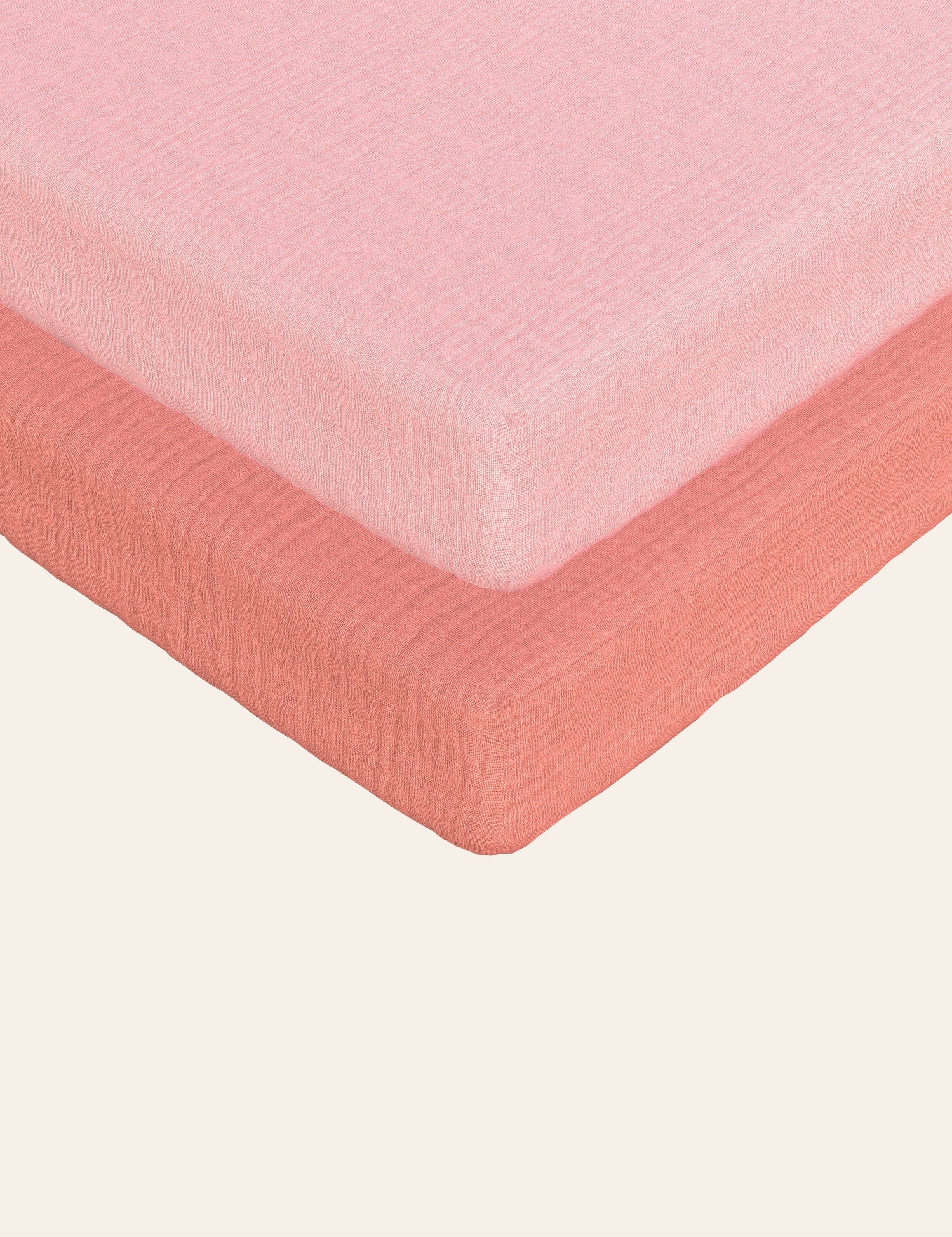 Solid coral and solid pink muslin bassinet sheets on a bed with a white background