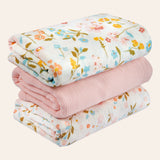 Stack of folded muslin baby swaddle blankets with floral patterns on a white background