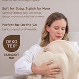 A mother wearing muslin nursing cover holding and nursing her baby