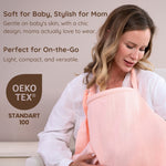 Mother breastfeeding her baby with a pink muslin nursing cover.