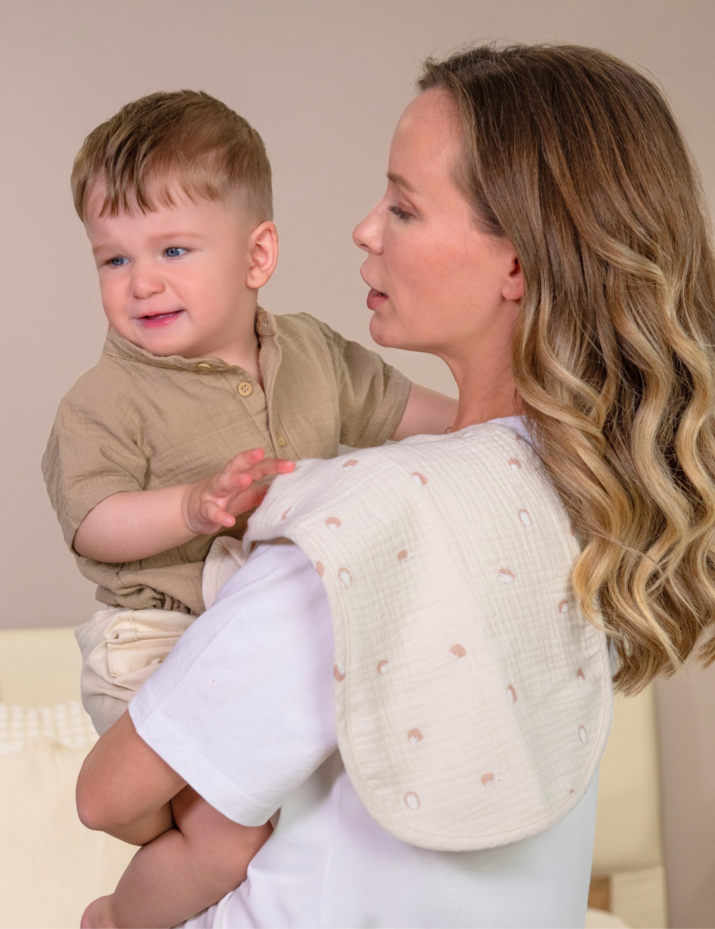 Mother holding her baby with hedgehog printed muslin burp clothes on her shoulder