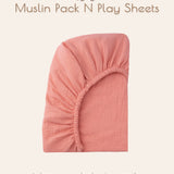 Solid coral muslin pack n play sheet on a beige background.