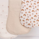 Three burp cloths, one solid beige, one with rainbow pattern and one with hedgehog illustrations.