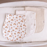 Three muslin burp cloths with different patterns displayed on a bassinet basket.